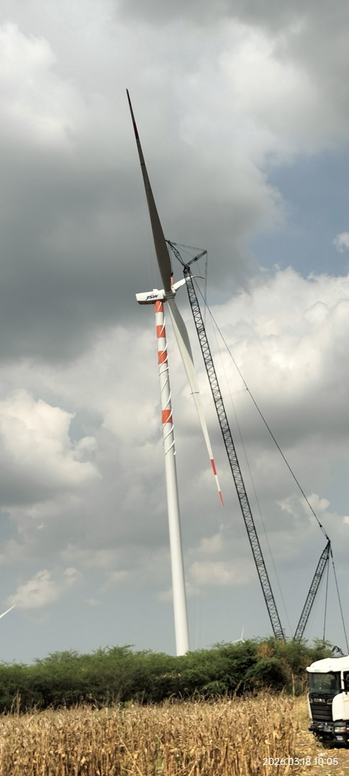 Wind turbine erection with crane under cloudy sky