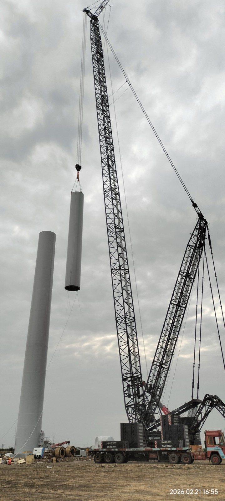 Crane lifting wind turbine tower sections at the site